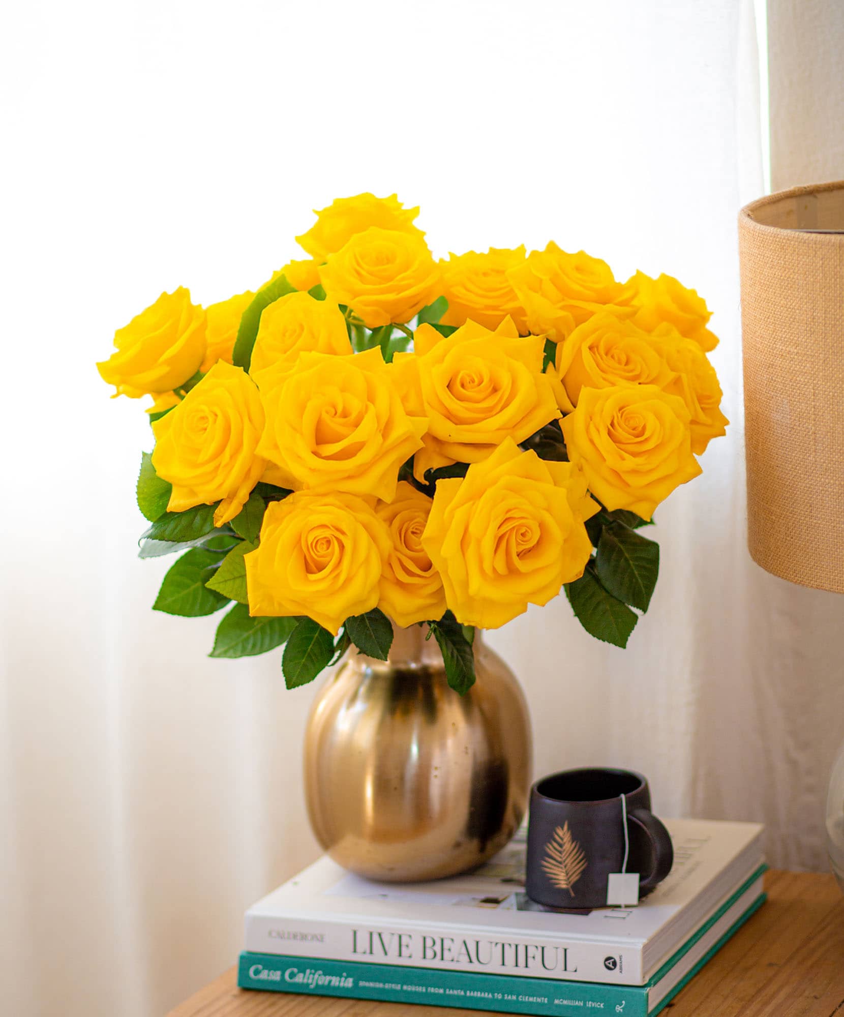 A vibrant bouquet of yellow roses in a golden vase, enhancing a cozy room decor.