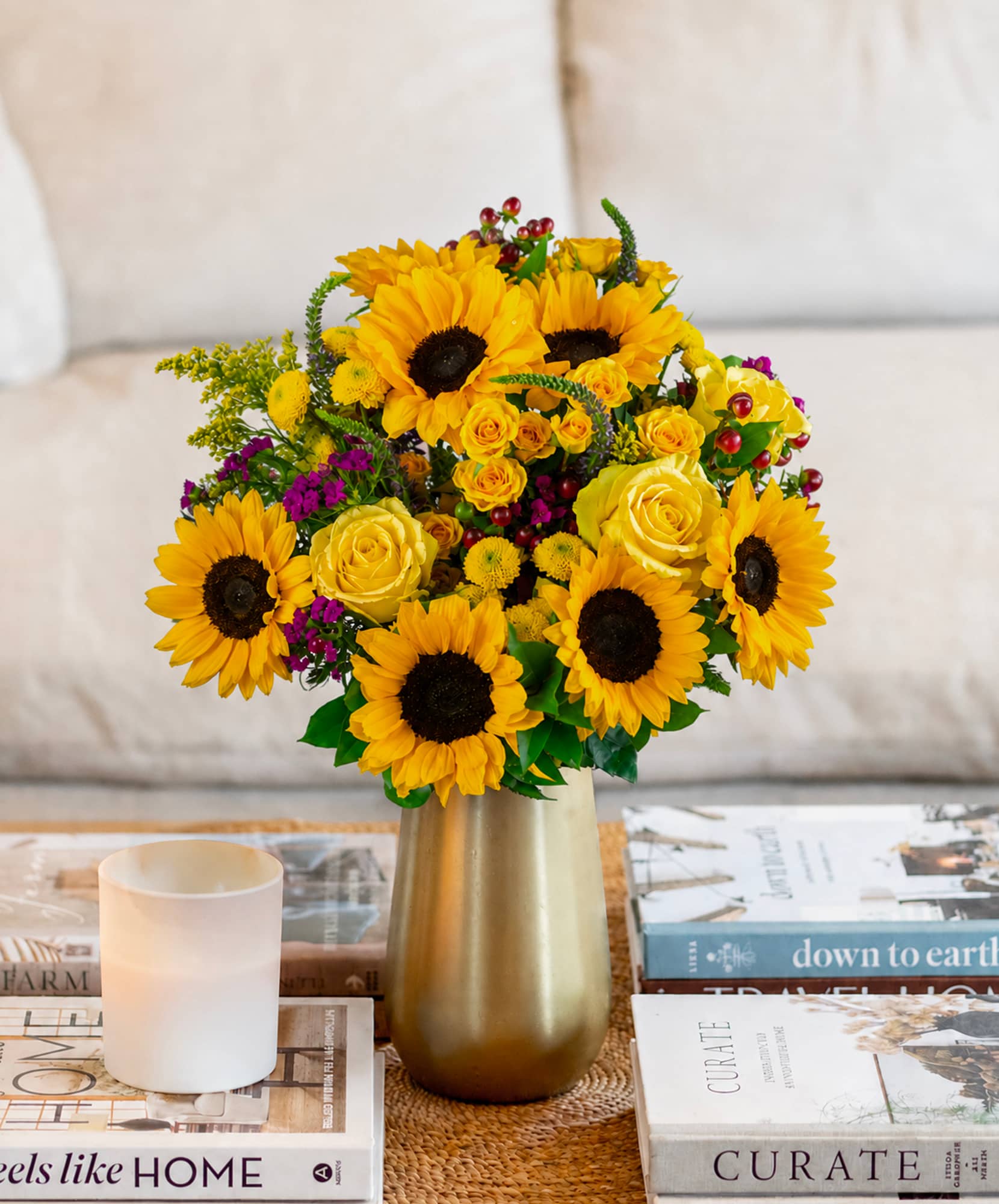 Vibrant sunflower bouquet with yellow roses and colorful accents in a chic vase.